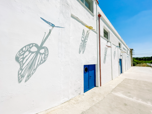 En la fachada de Neleman Winery, siete **esculturas de sombras** metálicas interactúan con la luz solar, proyectando patrones orgánicos y dando vida al espacio.